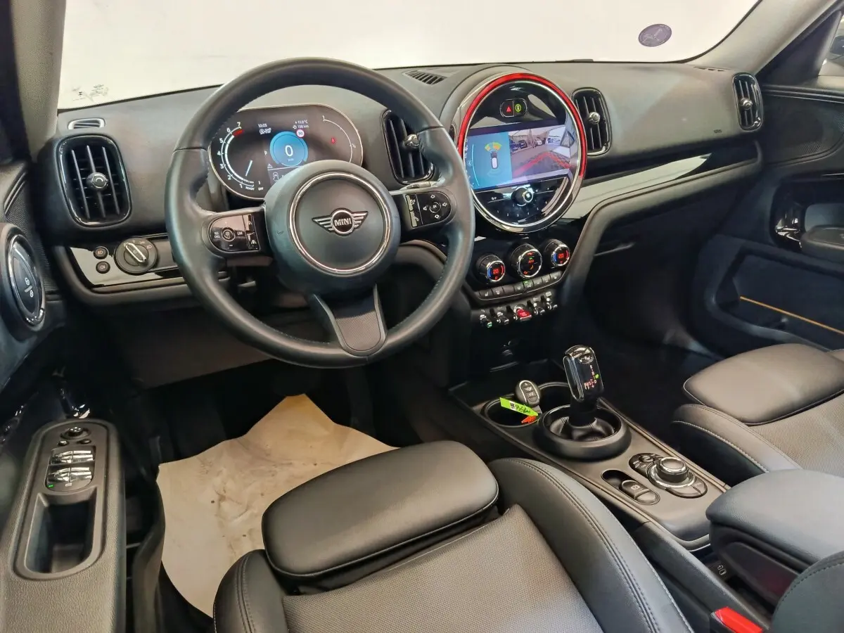 Vue intérieure avant droite du MINI Countryman 2023, tableau de bord noir avec écran tactile rond et volant cuir noir.