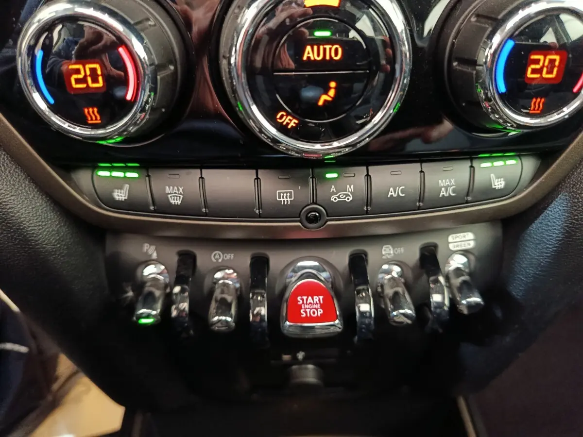 Gros plan sur la console centrale du MINI Countryman 2023, boutons chromés et bouton rouge Start Engine Stop.