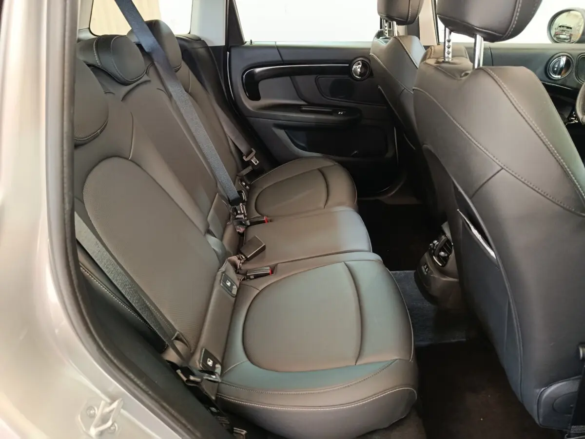 Vue intérieure côté gauche des sièges arrière en cuir noir du MINI Countryman 2023, avec ceinture de sécurité et garnitures de porte visibles.