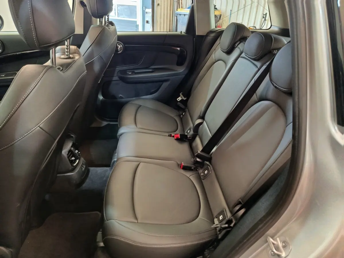 Vue intérieure côté droit des sièges arrière en cuir noir du MINI Countryman gris foncé 2023, avec appuie-têtes et ceintures visibles.