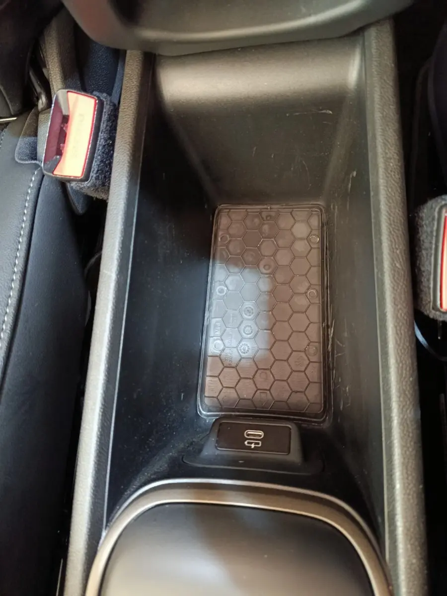 Vue rapprochée de la console centrale noire avec zone de recharge à induction et port USB-C du MINI Countryman gris foncé.