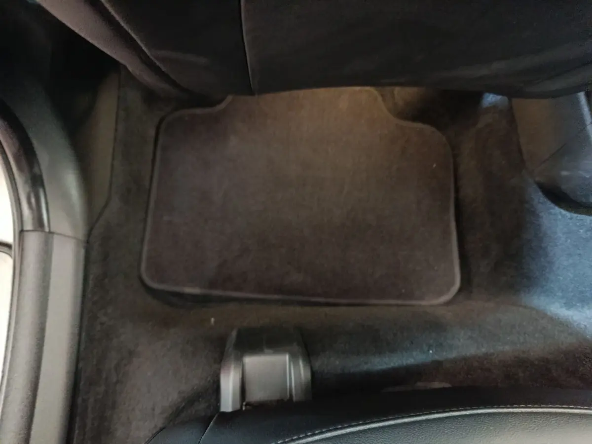 Vue intérieure du plancher côté passager avec tapis noir et partie inférieure du siège MINI Countryman gris foncé.