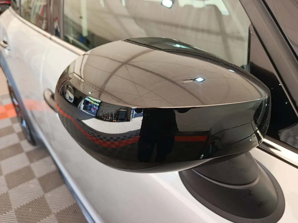 Rétroviseur droit noir brillant en gros plan sur MINI Countryman gris foncé, vue latérale partielle du véhicule.