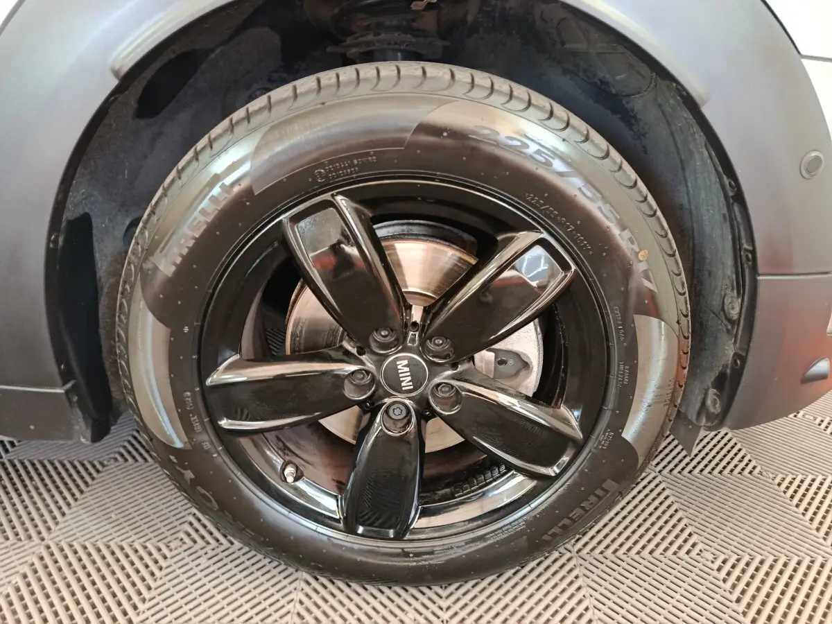 Gros plan sur la jante noire brillante et le pneu Pirelli d’un MINI Countryman gris foncé, côté avant droit.