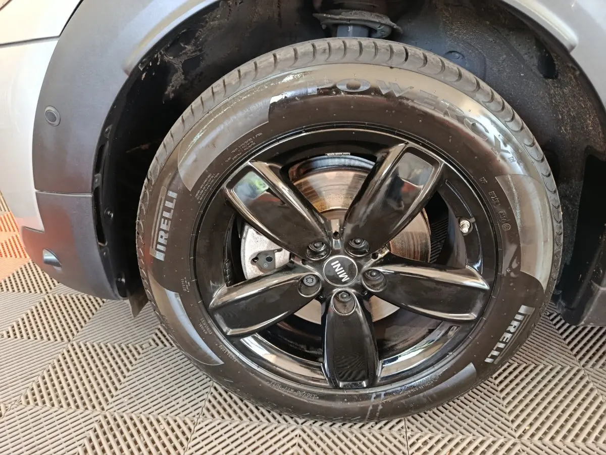 Gros plan sur la roue avant droite du MINI Countryman gris foncé, jante noire brillante à cinq branches.