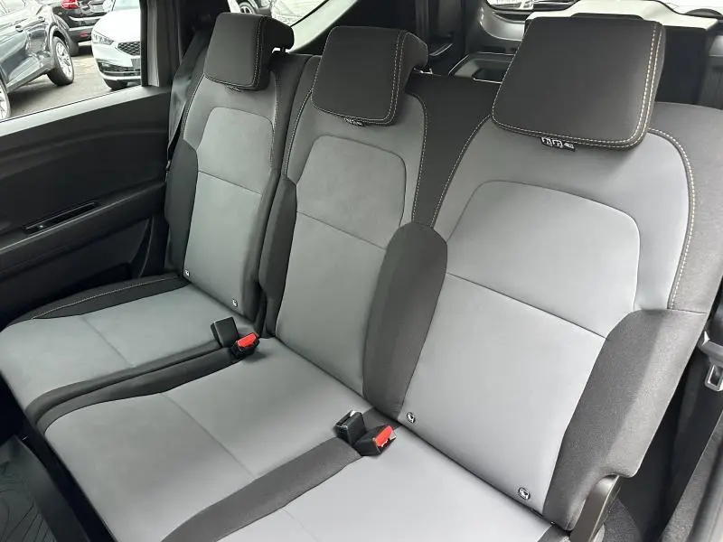 Vue rapprochée de la banquette arrière grise et noire du Dacia Jogger 2024 avec appuie-têtes intégrés et ceintures visibles.