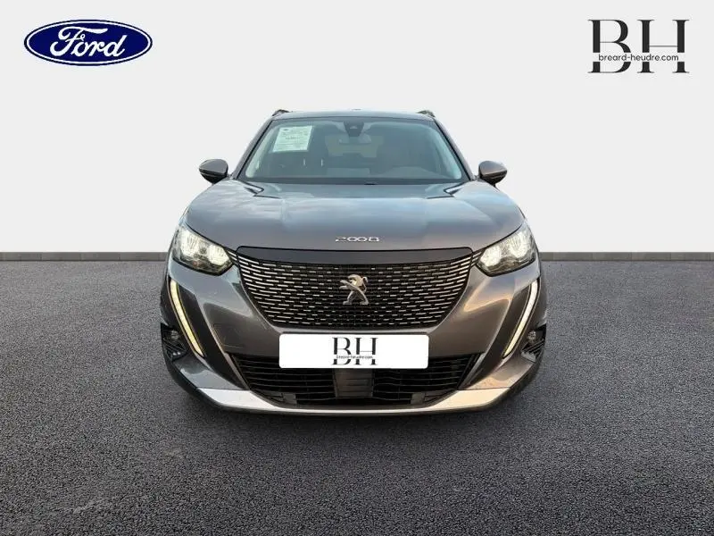 Vue avant d'une Peugeot 2008 2021 gris Artense avec calandre noire et feux LED allumés.