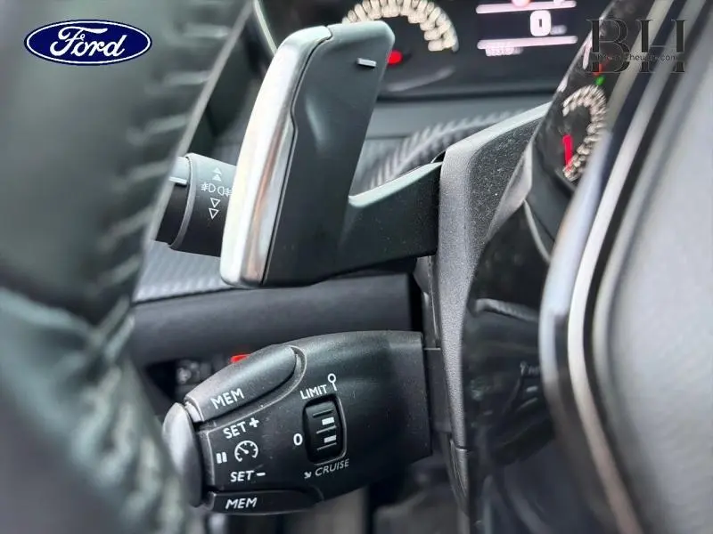 Gros plan sur la commande de régulateur de vitesse et palettes au volant d’un Peugeot 2008 gris Artense.