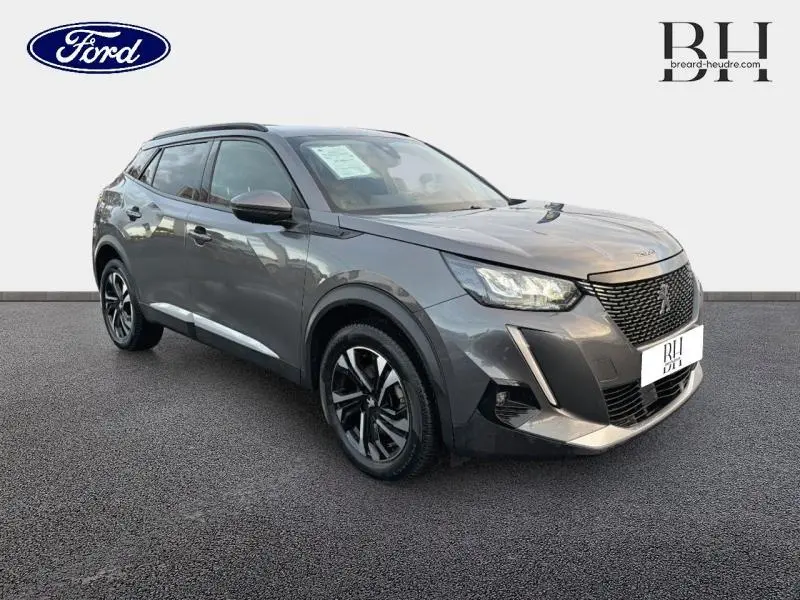 Peugeot 2008 gris Artense en 3/4 avant droit, mettant en valeur ses jantes alu et ses feux LED distinctifs.