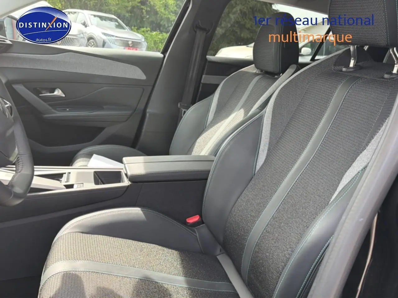 Vue intérieure côté droit montrant les sièges avant en tissu et cuir avec accoudoir central de la Peugeot 408 noire 2024.