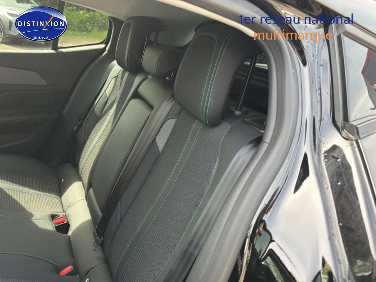Vue intérieure côté arrière droit montrant la banquette arrière noire avec surpiqûres vertes du Peugeot 408 Hybrid 136 allure e-dcs6 2024.