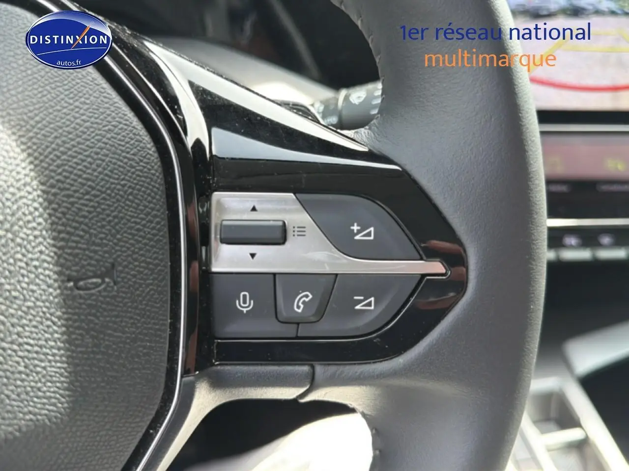 Gros plan sur les commandes gauche du volant cuir noir du Peugeot 408 Hybrid 2024 avec écran tactile en arrière-plan.