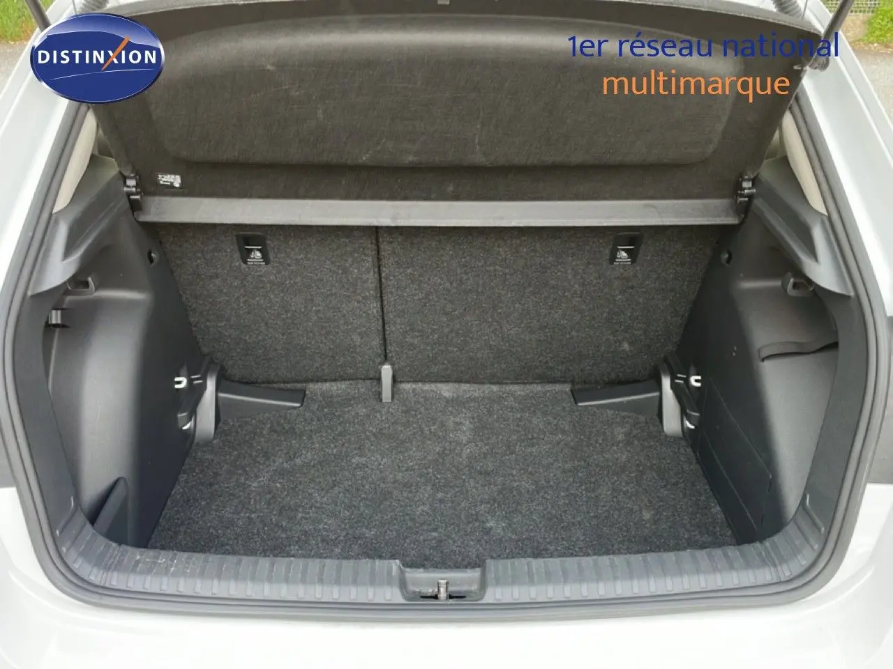 Coffre ouvert vu de l'arrière d'une Skoda Fabia blanc glacier 2025, montrant l'espace de rangement vide et la moquette grise.