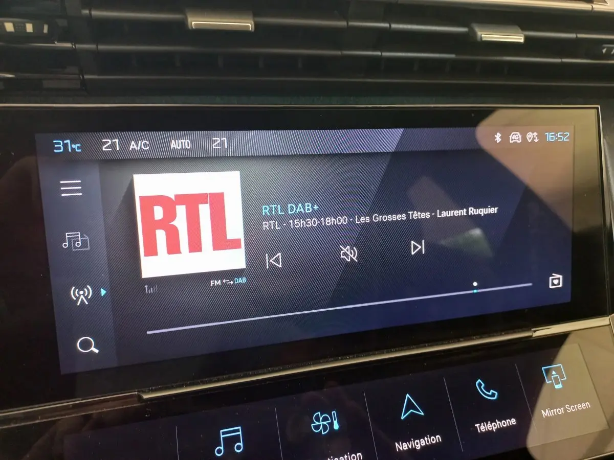 Écran tactile central de la Peugeot 308 bleu, affichant la radio RTL avec commandes multimédia visibles.