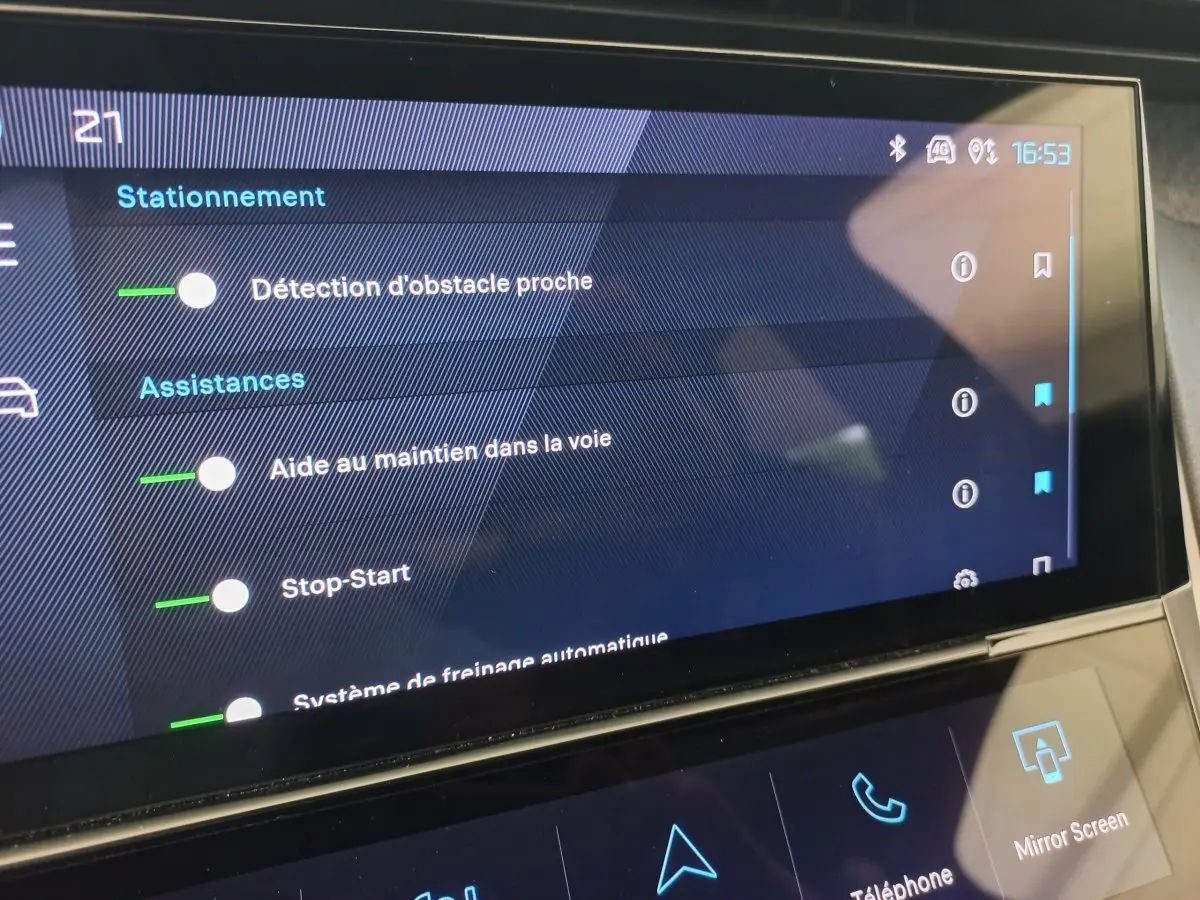 Écran tactile intérieur de la Peugeot 308 bleu, affichant les options d’assistance à la conduite et stationnement.