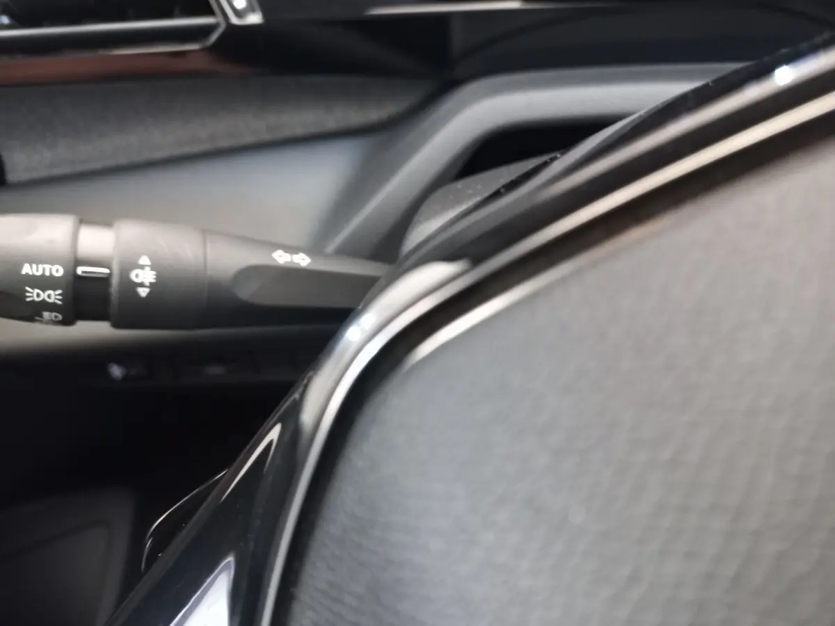 Gros plan sur le volant cuir noir multifonctions et la commande des feux dans l’habitacle d’une Peugeot 308.
