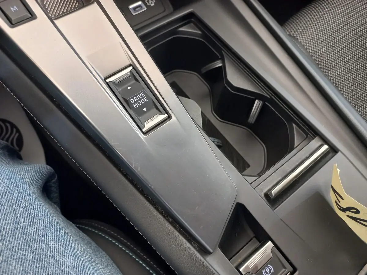 Vue rapprochée de la console centrale noire de la Peugeot 308 bleu, avec bouton Drive Mode et frein à main électrique.