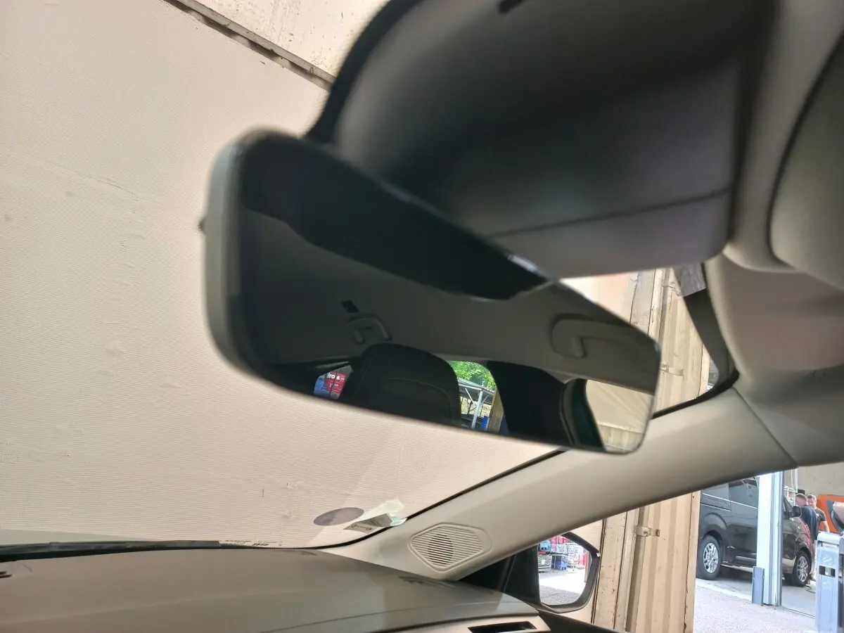 Vue intérieure du rétroviseur central d'une Peugeot 308 bleu, avec partie du tableau de bord et pare-brise visible.