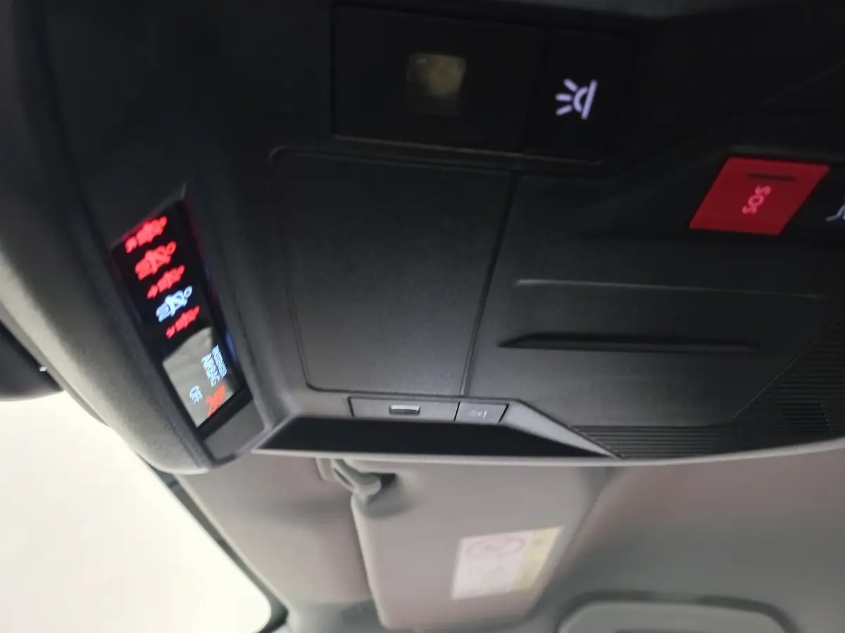Vue intérieure en gros plan du panneau de commandes au plafond avec bouton SOS rouge dans une Peugeot 308 bleu.