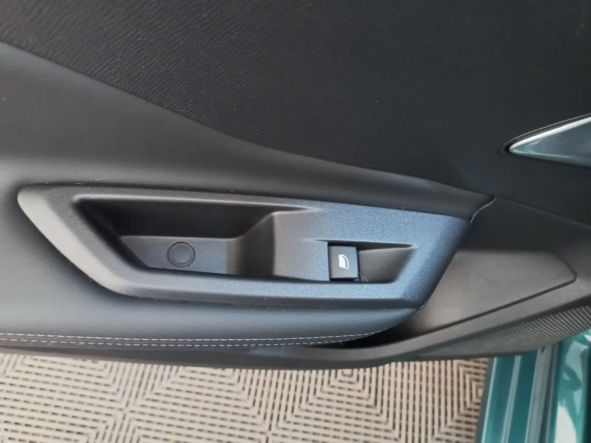 Poignée intérieure de porte côté gauche en plastique noir sur Peugeot 308 bleu, vue rapprochée.