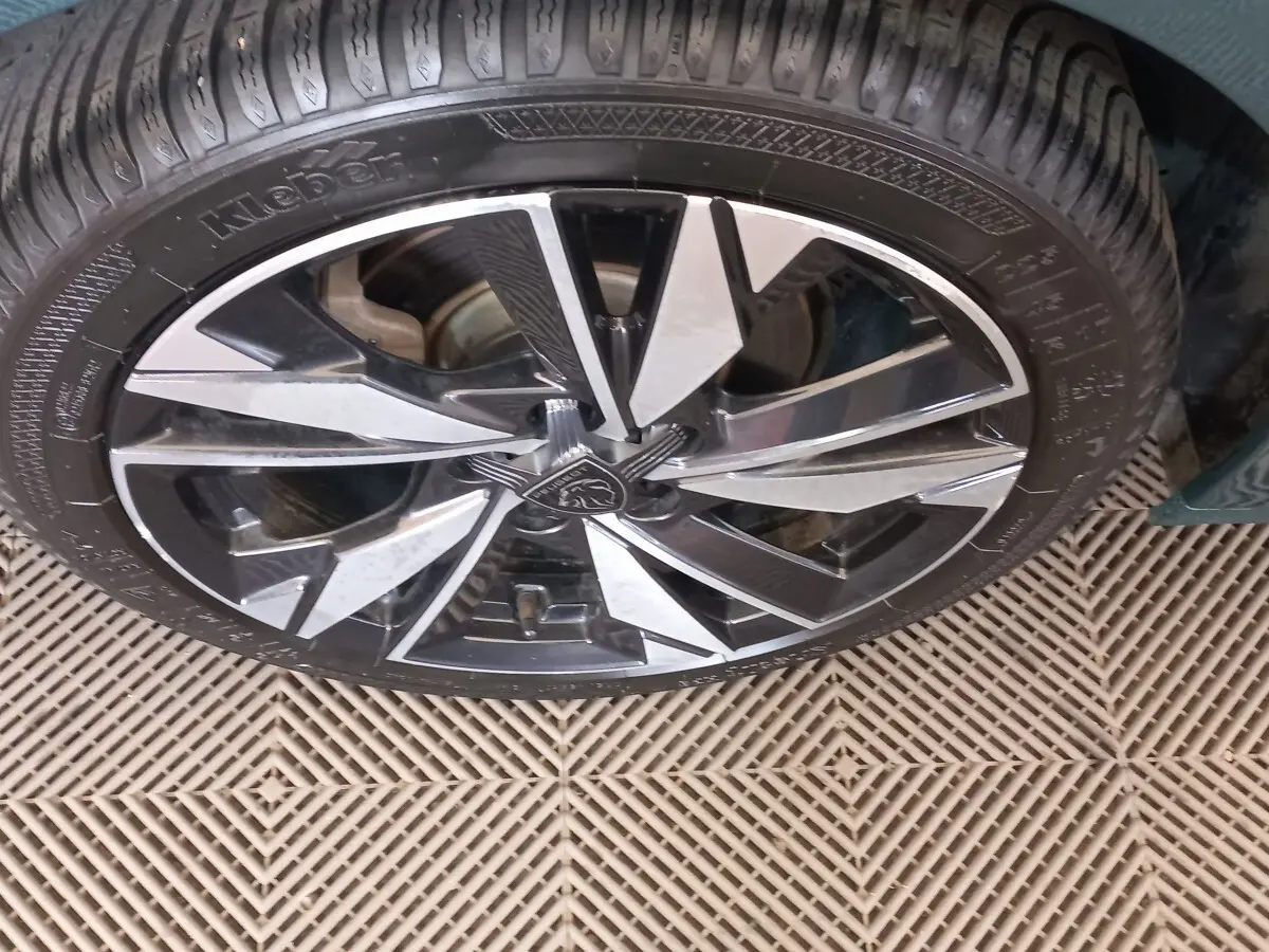 Gros plan sur la roue avant droite de la Peugeot 308 bleu, avec jante alliage noire et argentée au design moderne.