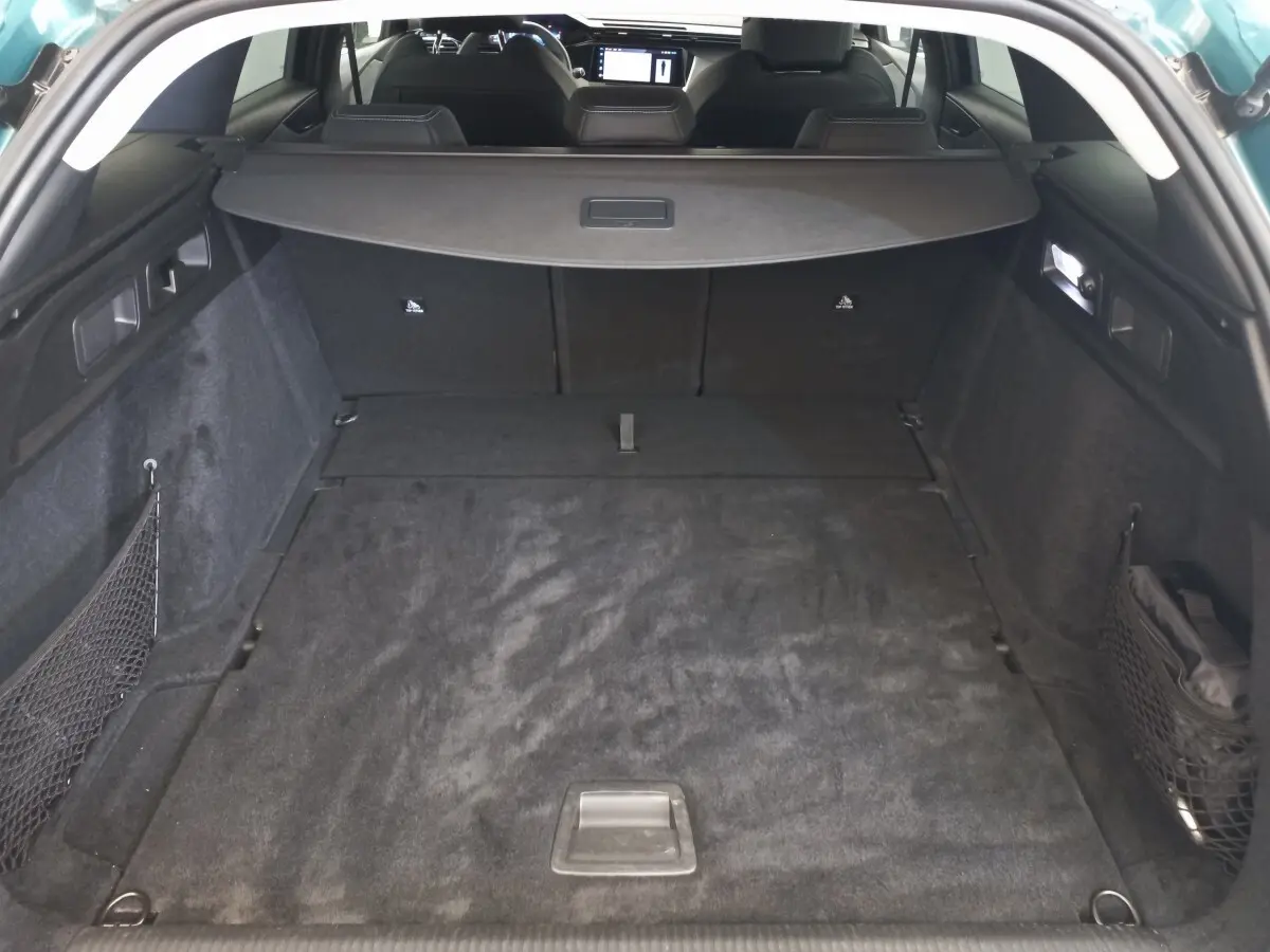 Vue de l'intérieur du coffre spacieux et noir de la Peugeot 308 bleu, avec banquette arrière rabattue et cache-bagages.