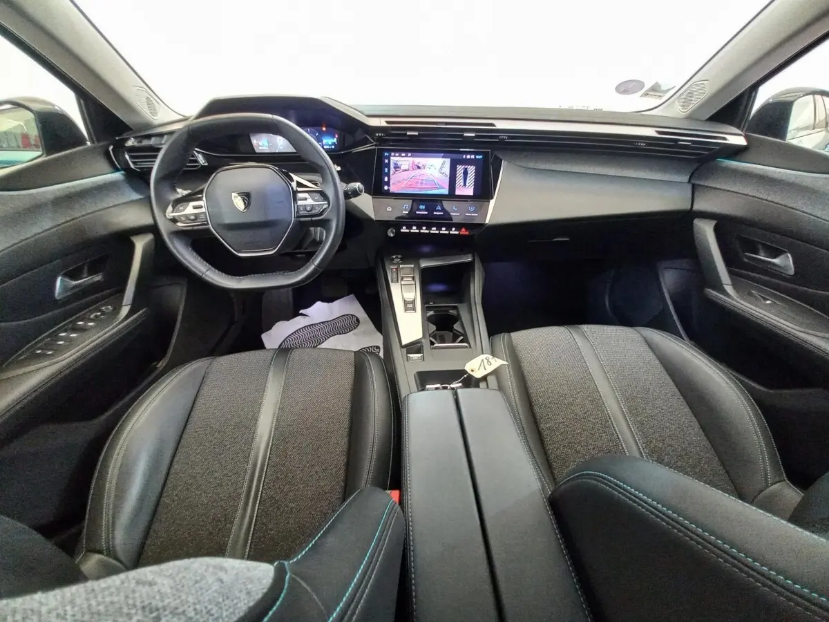 Vue intérieure avant de la Peugeot 308 PureTech 130 bleu, avec volant cuir multifonctions et écran tactile central.
