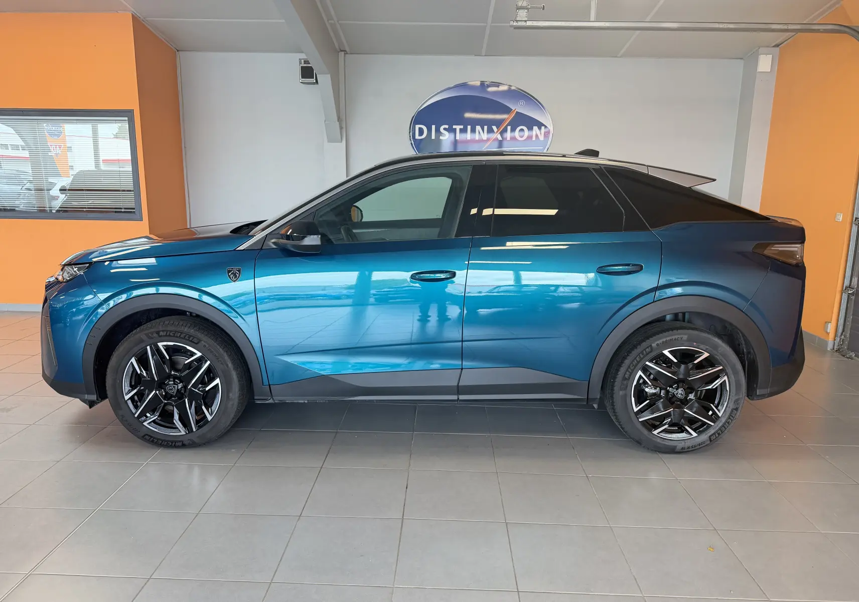 Vue latérale droite d’un Peugeot 3008 Hybrid 145 GT bleu Obsession avec toit noir et jantes alliage 19 pouces en intérieur showroom.