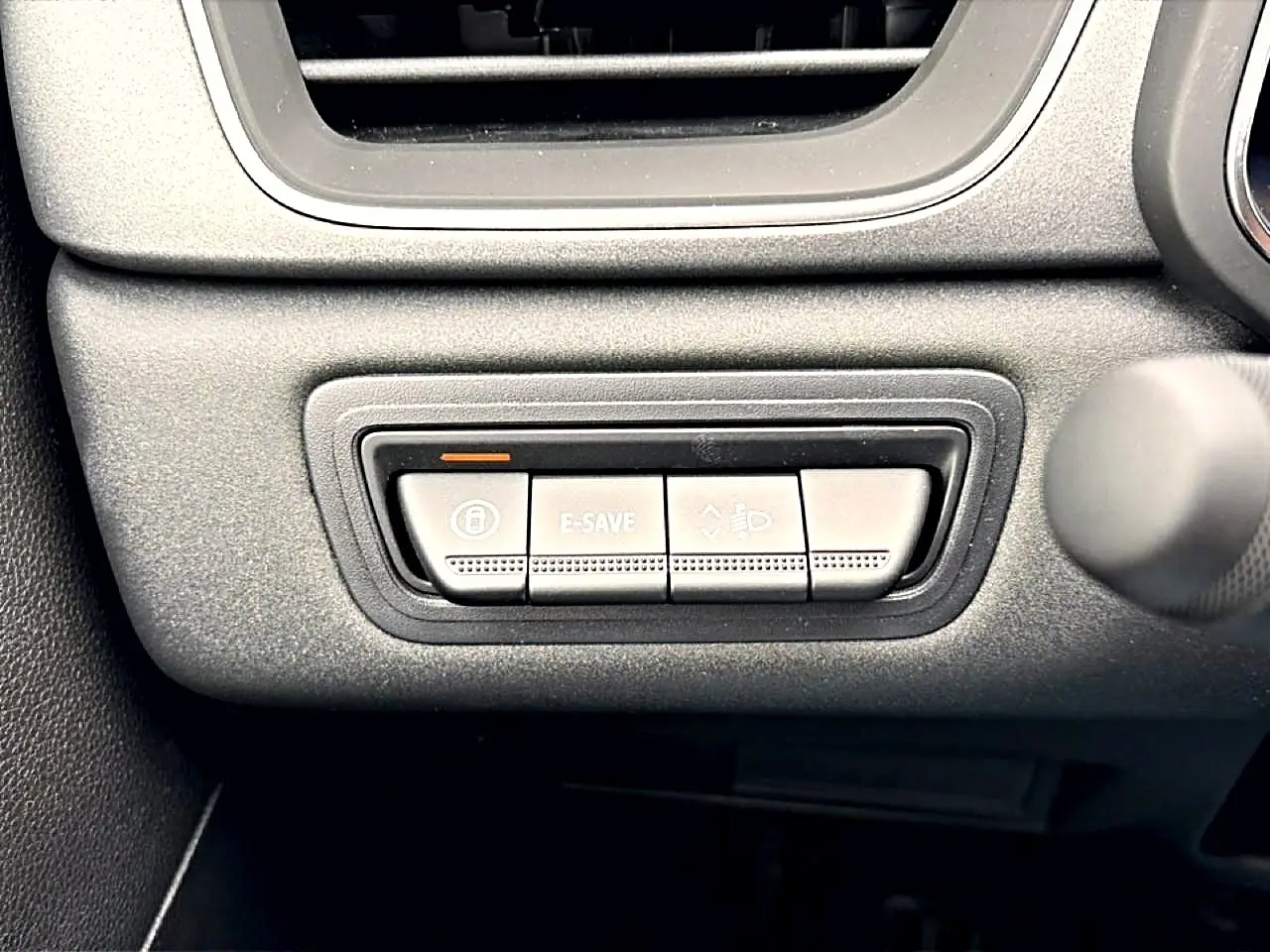Gros plan sur les boutons de commande noirs sous la ventilation intérieure du Renault Symbioz 1.8 e-tech bleu mercure.