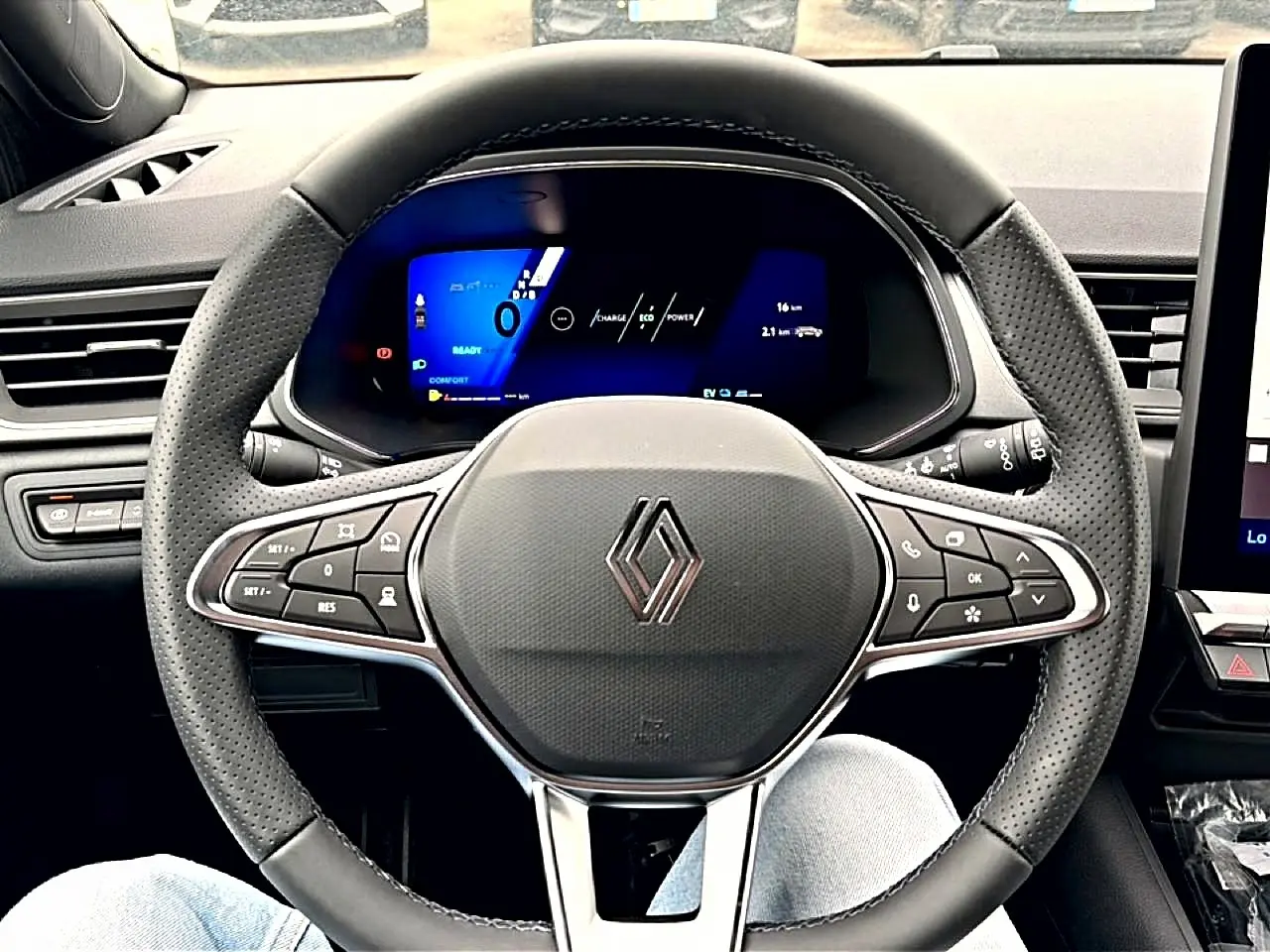 Vue frontale du volant perforé de la Renault Symbioz 2026 avec tableau de bord numérique bleu et commandes intégrées.