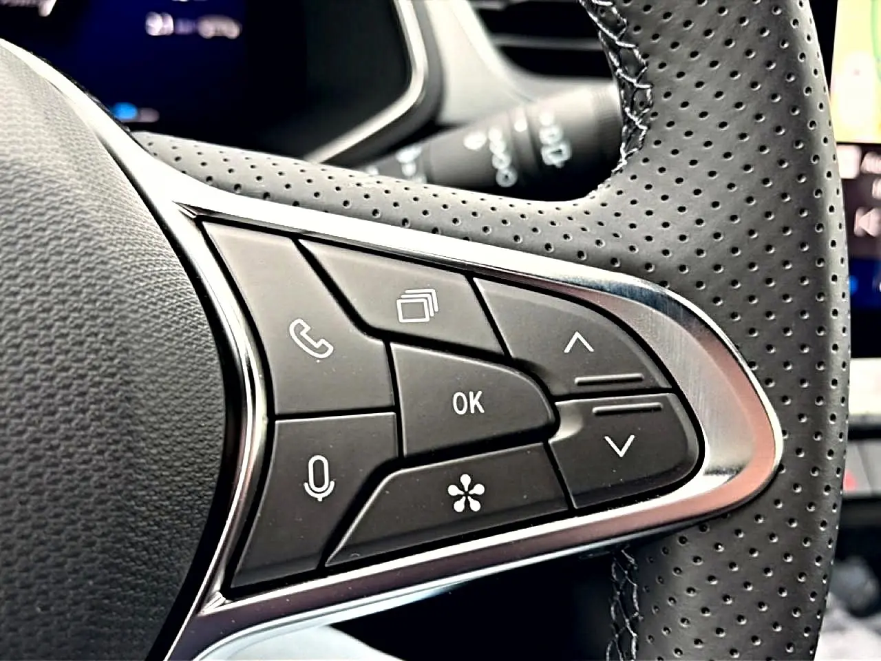 Gros plan sur les commandes multifonctions noires et argentées du volant perforé du Renault Symbioz bleu mercure.