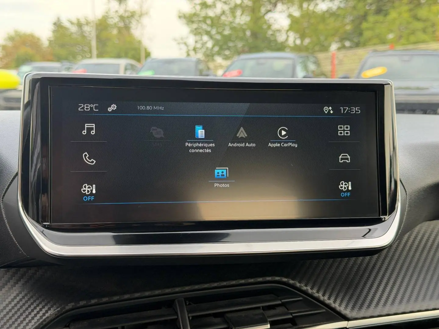 Écran tactile central du tableau de bord du Peugeot 208 1.2 Hybrid blanc, affichant Android Auto et Apple CarPlay.