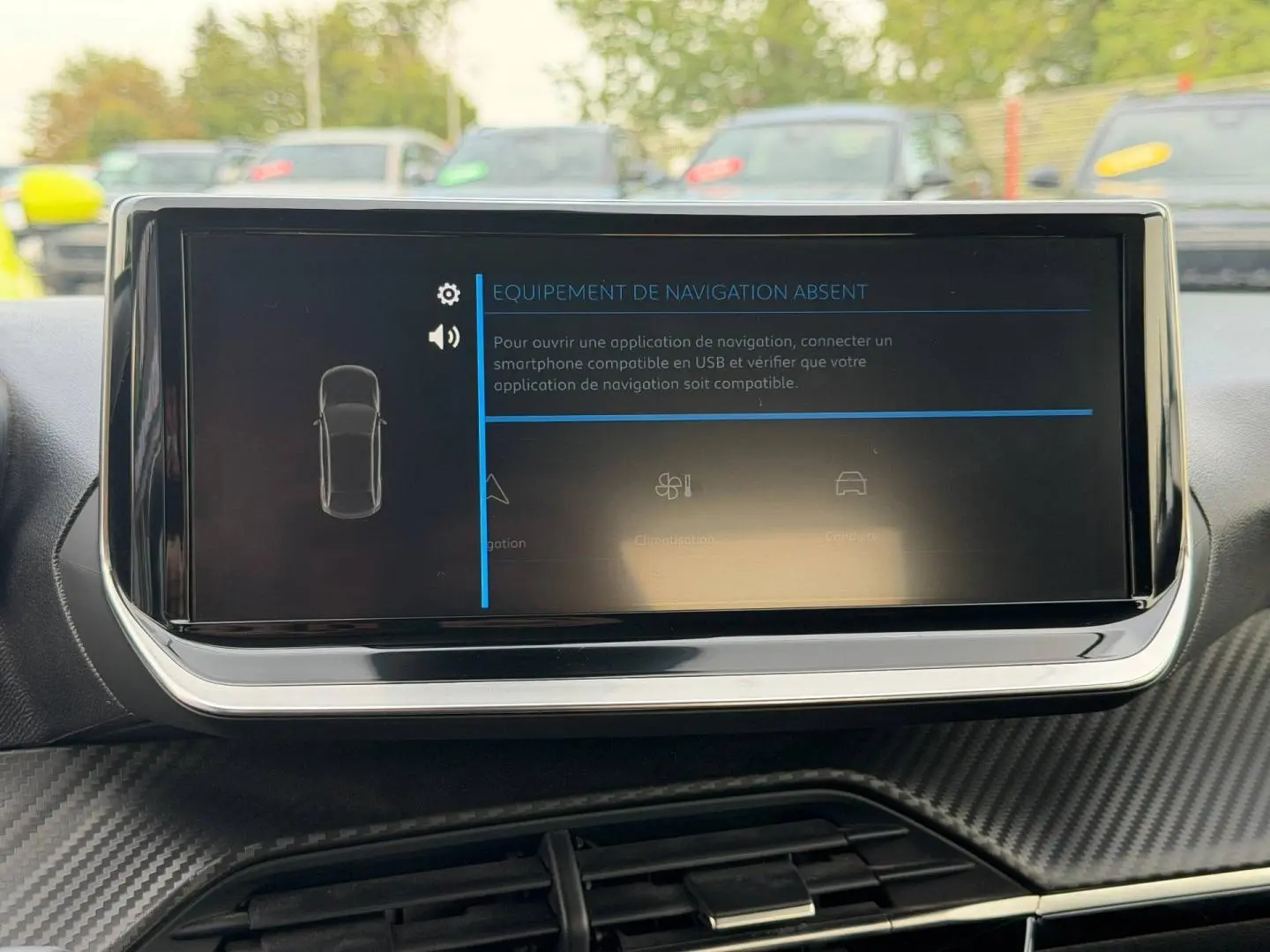 Écran tactile central de la Peugeot 208 blanc Okénite, vue intérieure frontale sur la console avec finition carbone.