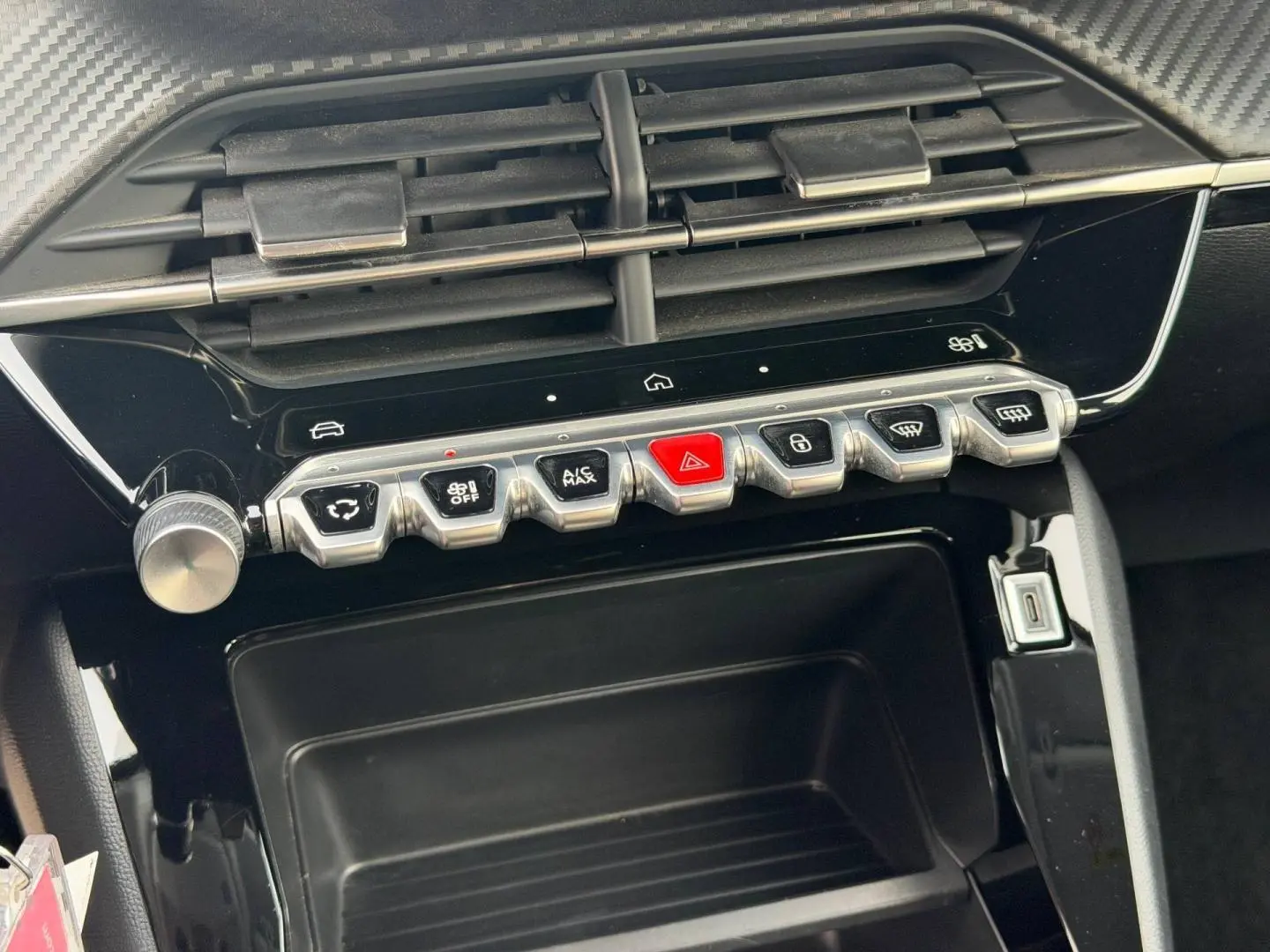 Vue rapprochée de la console centrale noire avec commandes piano et prise USB du Peugeot 208 blanc Okénite.