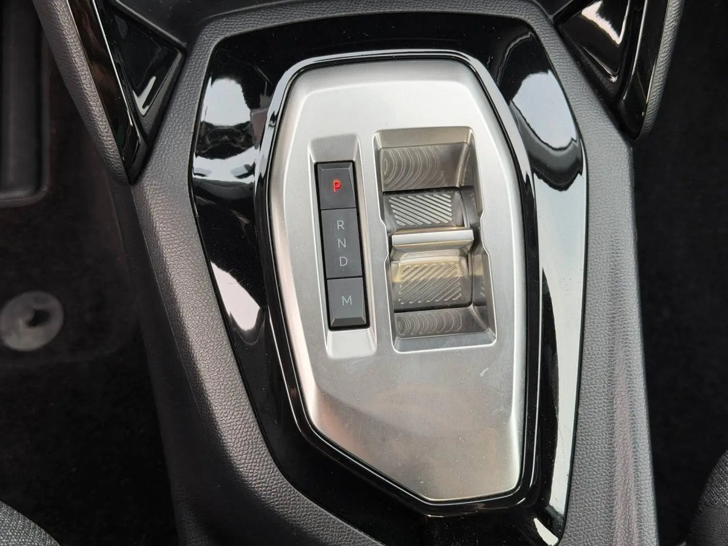Vue rapprochée de la commande de boîte automatique noire et argentée de la Peugeot 208 blanche Okénite.