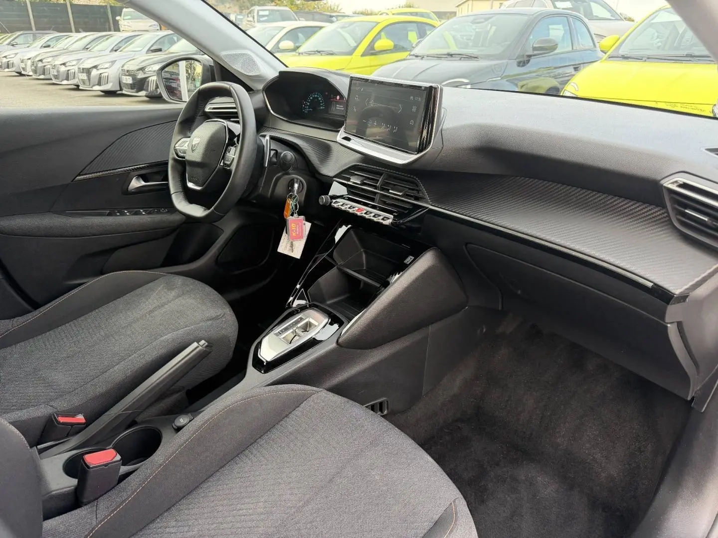 Intérieur avant droit de la Peugeot 208 1.2 Hybrid 110ch Style 2025 avec tableau de bord noir et écran tactile central.