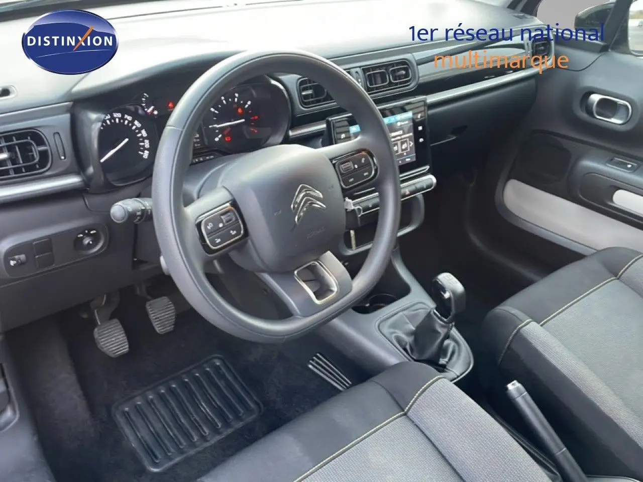 Vue intérieure côté conducteur de la Citroën C3 sable métal 2022, avec volant multifonction et boîte manuelle.