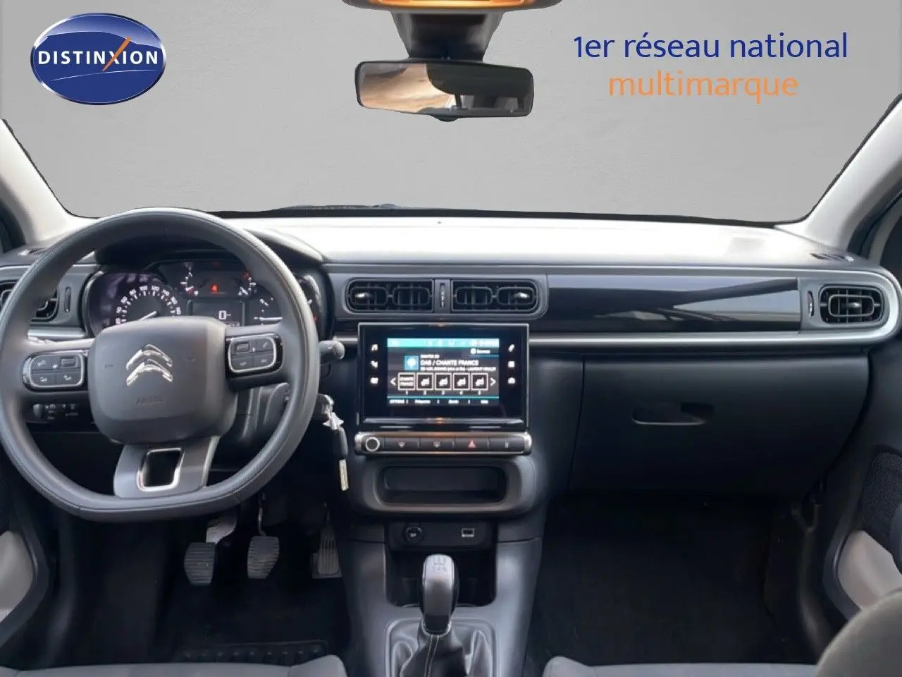 Vue frontale de l'intérieur de la Citroën C3 2022, tableau de bord noir avec écran tactile central et volant multifonction.