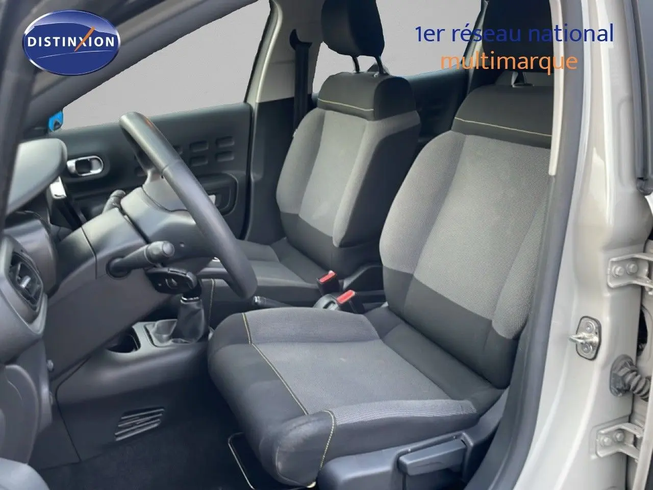 Vue intérieure côté conducteur de la Citroën C3 2022 sable métal, montrant les sièges en tissu gris et la boîte manuelle.