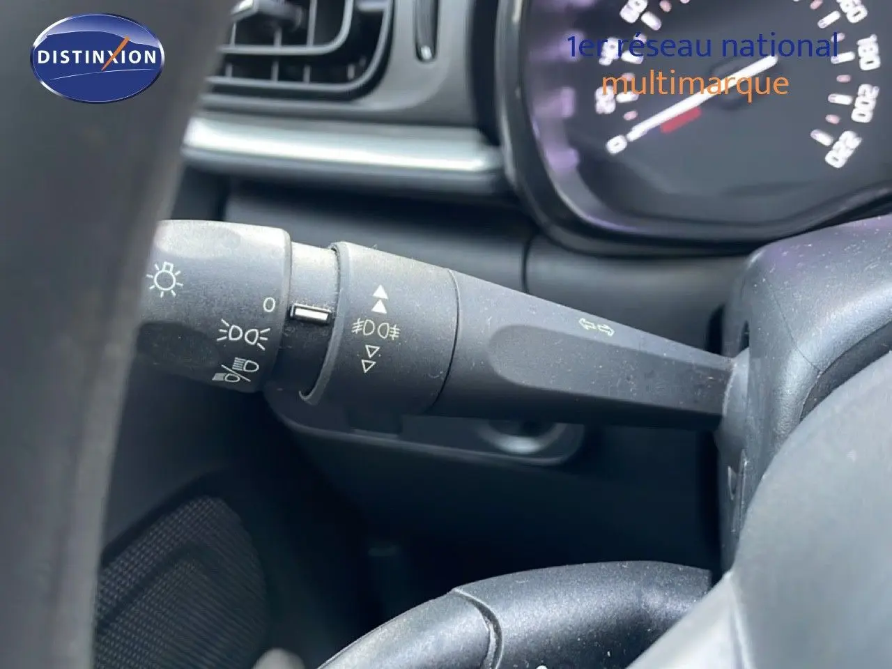 Gros plan sur la manette de commande des phares à gauche du volant dans l’habitacle d’une Citroën C3 sable métal.
