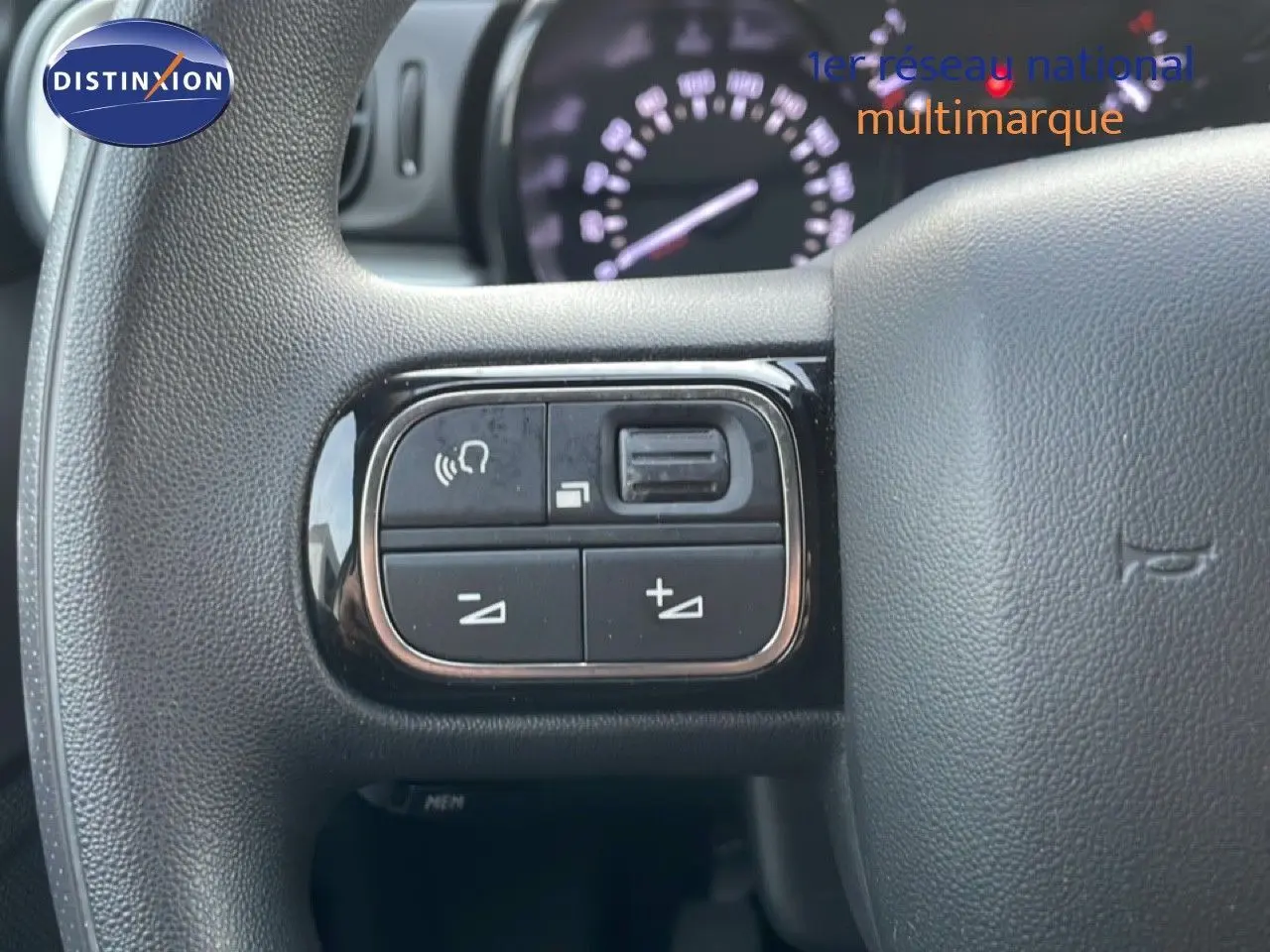 Gros plan sur les commandes au volant d'une Citroën C3 2022 sable métal, avec tableau de bord flou en arrière-plan.