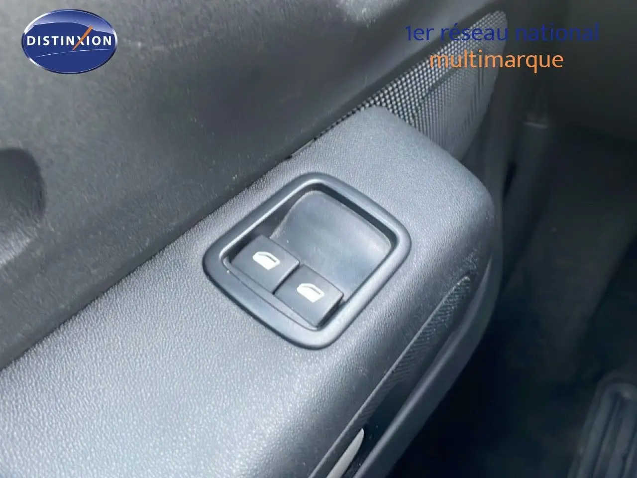 Gros plan sur les commandes des vitres électriques côté conducteur d’une Citroën C3 2022 finition sable métal.