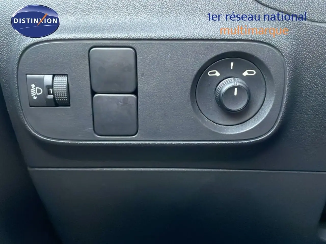Gros plan sur les commandes de réglage des rétroviseurs et des phares, intérieur noir de la Citroën C3 sable métal.