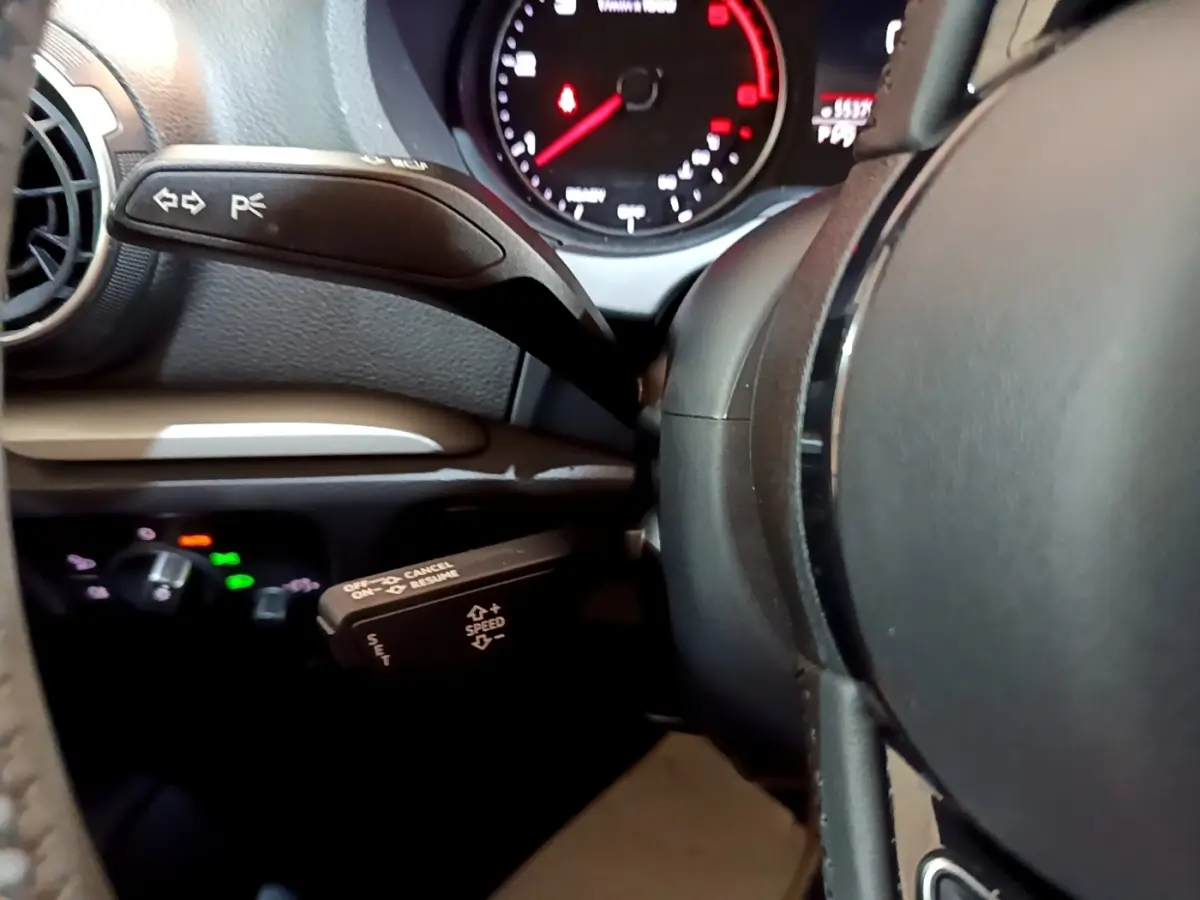 Gros plan sur le volant cuir noir et les commandes au volant de l'Audi A3 30 TDI 2019, tableau de bord partiellement visible.