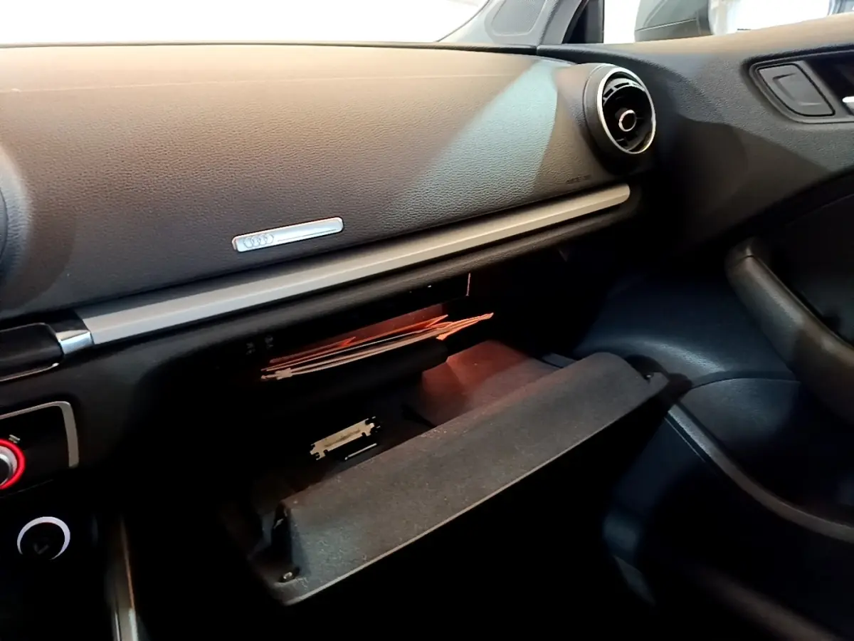 Intérieur de l'Audi A3 30 TDI 2019, vue côté passager sur la boîte à gants ouverte et la planche de bord noire.