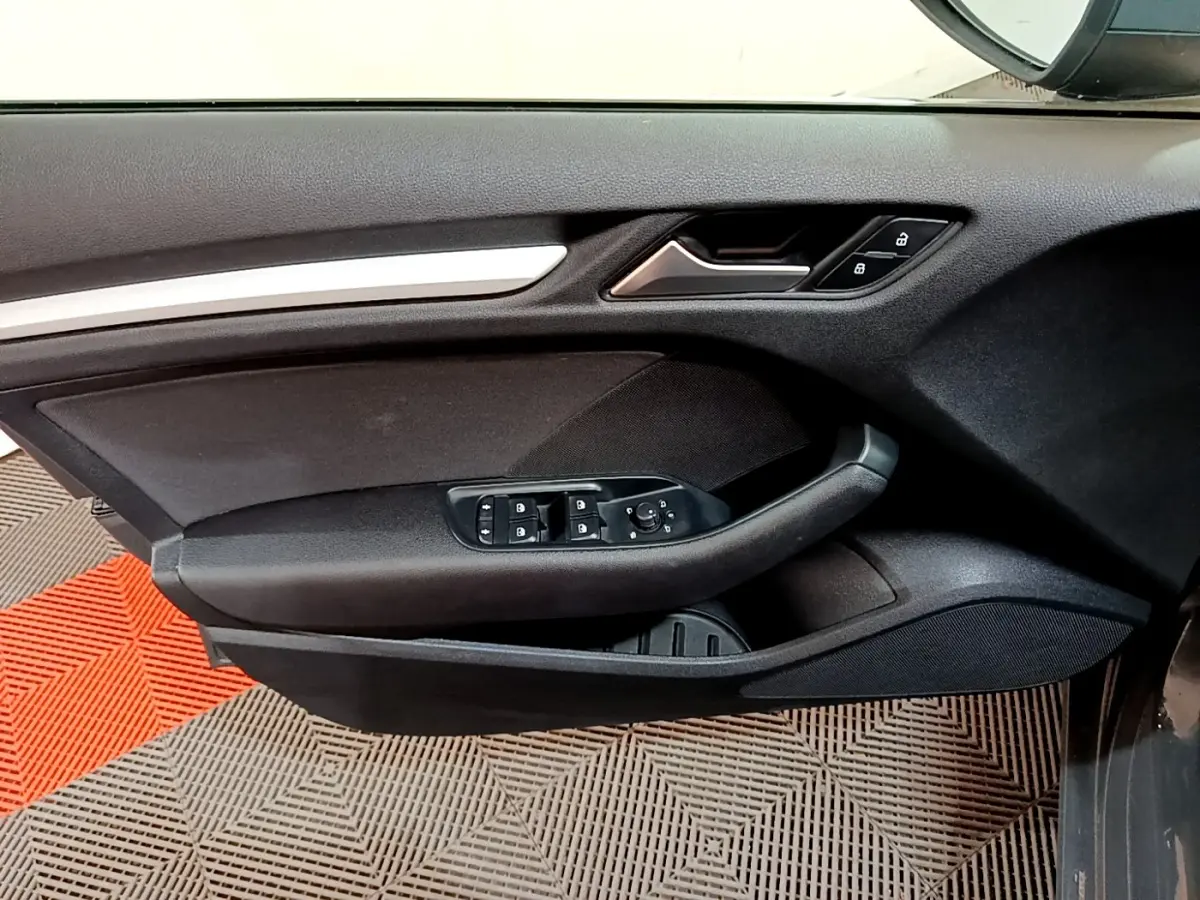 Vue rapprochée de la porte avant gauche d’une Audi A3 gris foncé, avec commandes électriques et verrouillage central.