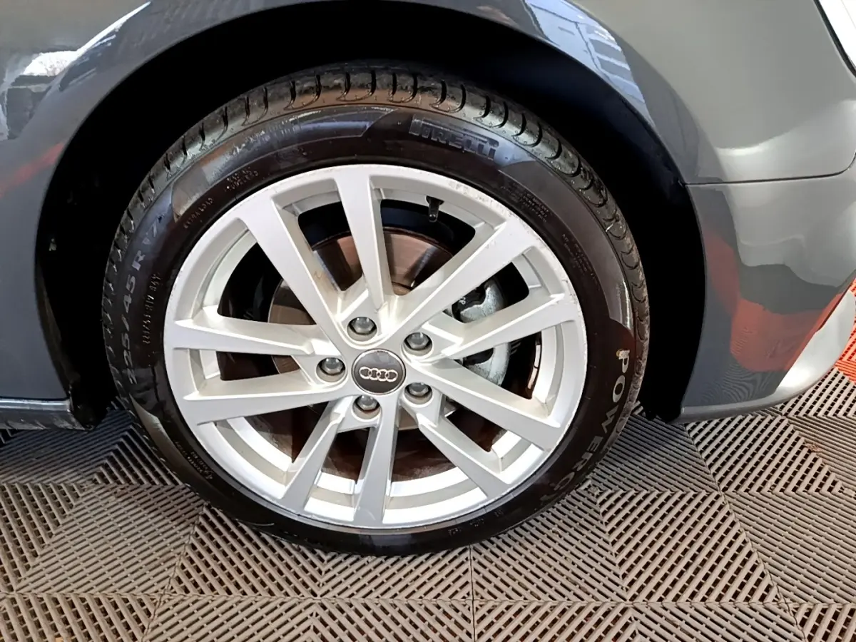 Gros plan sur la roue avant droite d'une Audi A3 gris foncé, jante alliage à plusieurs branches, pneu Pirelli visible.