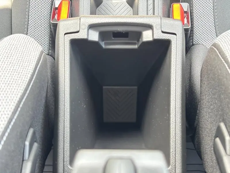 Vue rapprochée de l'accoudoir central ouvert entre les sièges avant du Dacia Bigster blanc, montrant le rangement intérieur.