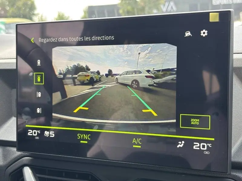 Vue arrière sur l'écran de caméra de recul montrant un Dacia Bigster blanc en stationnement avec lignes de guidage vertes.