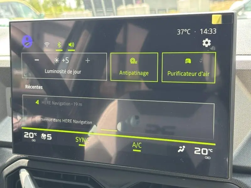 Écran tactile central du tableau de bord du Dacia Bigster blanc, affichant les réglages climatisation et fonctions antipatinage et purificateur d'air.